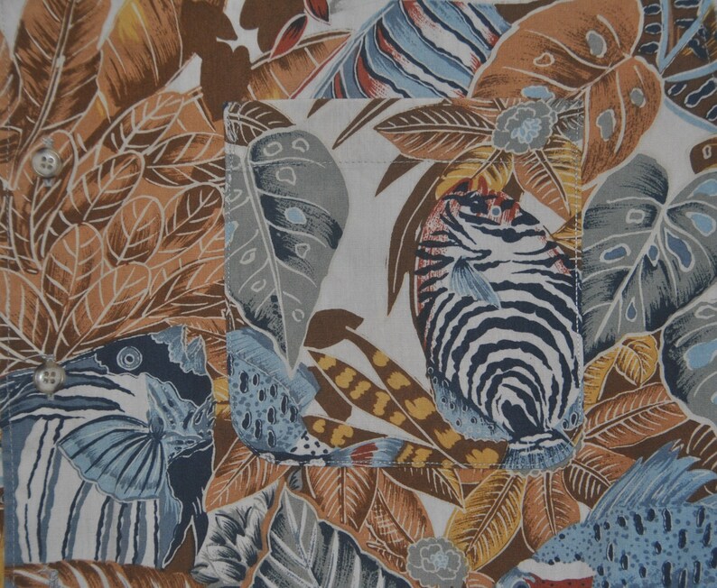 May include: A white fabric with a tropical print featuring brown, blue, and white fish, leaves, and flowers.