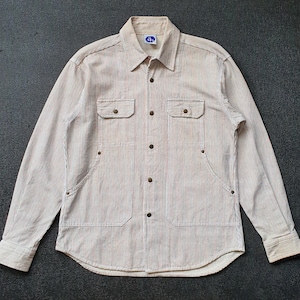 May include: Beige and white striped button-up shirt with two chest pockets and two lower pockets. The long-sleeved shirt has a collared neckline and a small blue tag near the collar. The shirt is made of a textured fabric.