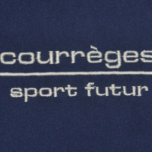 Puede incluir: Un parche bordado azul marino con el texto "courr&egrave;ges sport futur" en blanco.