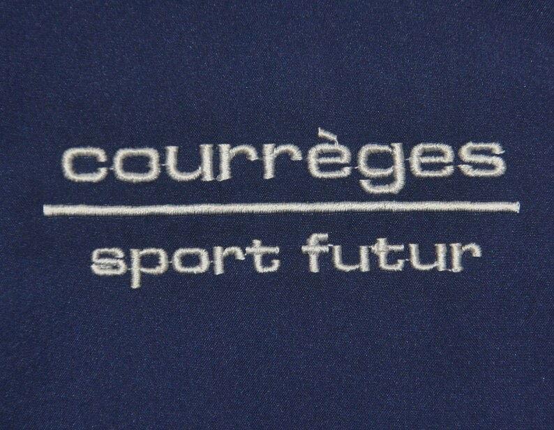 Puede incluir: Un parche bordado azul marino con el texto "courr&egrave;ges sport futur" en blanco.