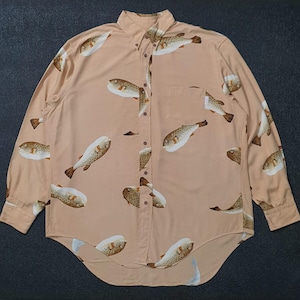K&ouml;nnte beinhalten: Hellbeige Hemd mit Kn&ouml;pfen und einem sich wiederholenden Muster aus braunen und wei&szlig;en Kugelfischen. Das lang&auml;rmlige Hemd hat eine Brusttasche und einen klassischen Kragen.