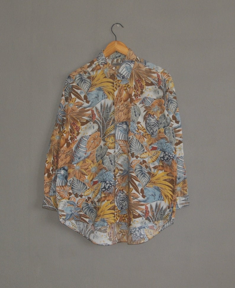 May include: A long-sleeved button-up shirt with a white background and a colorful tropical print featuring birds, leaves, and flowers.