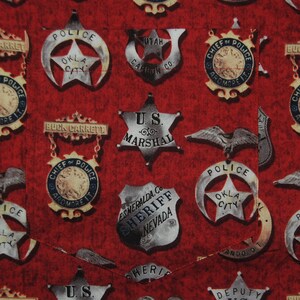 Pode incluir: Tecido vermelho com um padr&atilde;o de distintivos de pol&iacute;cia e xerife vintage. Os distintivos, em forma de estrela e escudo, trazem textos como "U.S. Marshal" e "Okla City Police".
