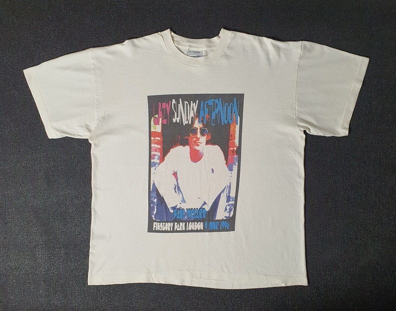 Pode incluir: Camiseta branca com um gr&aacute;fico colorido de um homem com &oacute;culos de sol e o texto "Lazy Sunday Afternoon" e "Paul Weller" e "Finsbury Park London 8 June 1994".