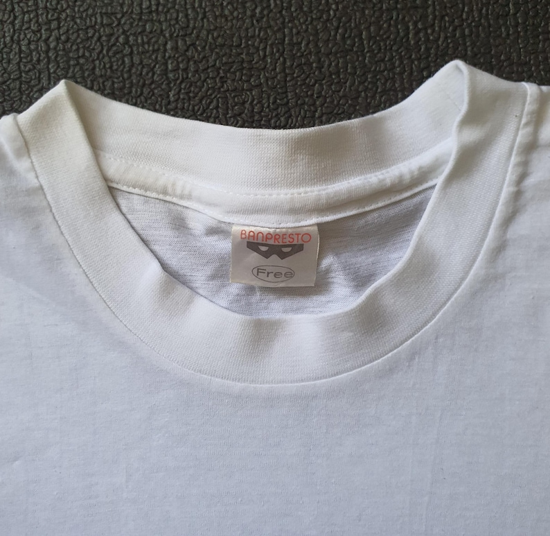 May include: White t-shirt with a Banpresto label featuring a black mask logo and the word "Free".
