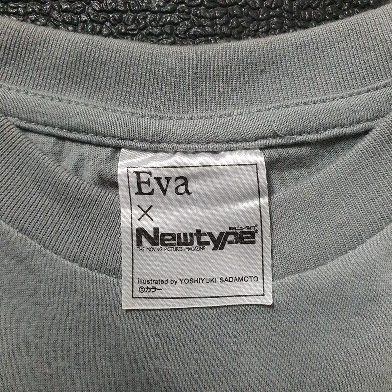 May include: A white tag with black text that reads "Eva x Newtype The Moving Pictures Magazine Illustrated by Yoshiyuki Sadamoto &copy;カラー".