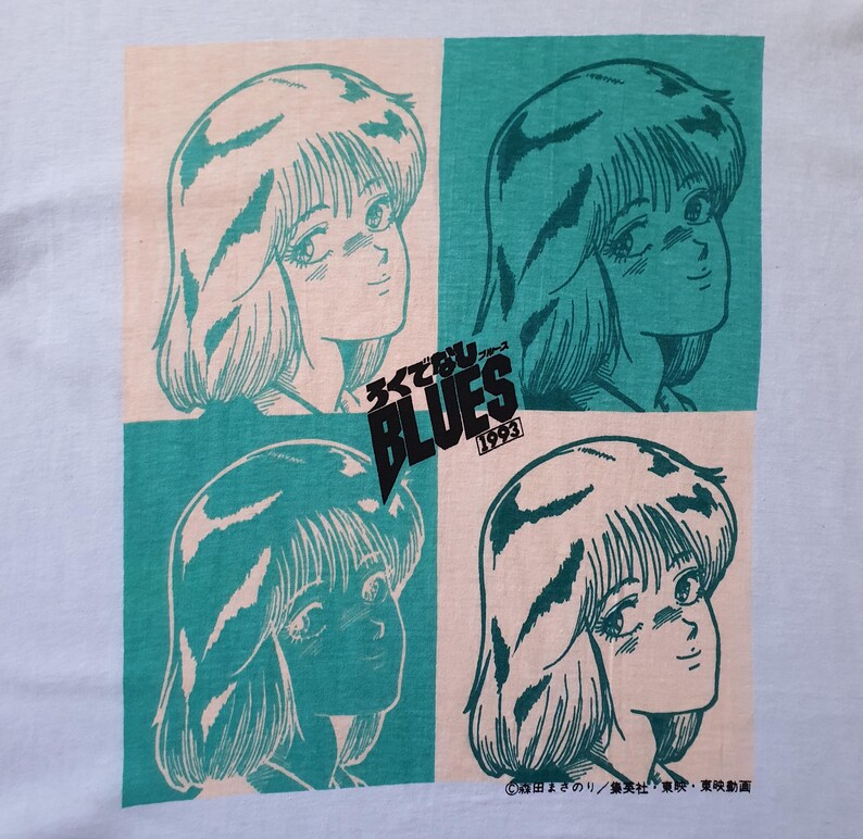 May include: A light blue t-shirt with a repeated image of a girl with long, dark hair. The image is in a teal and pink color scheme. The text "シティ・ブルース" and "BLUES 1993" is printed on the shirt.