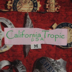 Pode incluir: Camisa vermelha estampada com distintivos e estrelas da pol&iacute;cia. A etiqueta rosa diz "California Tropic USA" e o tamanho &eacute; "M".
