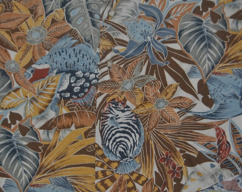 May include: A white fabric with a tropical print featuring blue and brown fish, yellow and brown flowers, and green leaves.