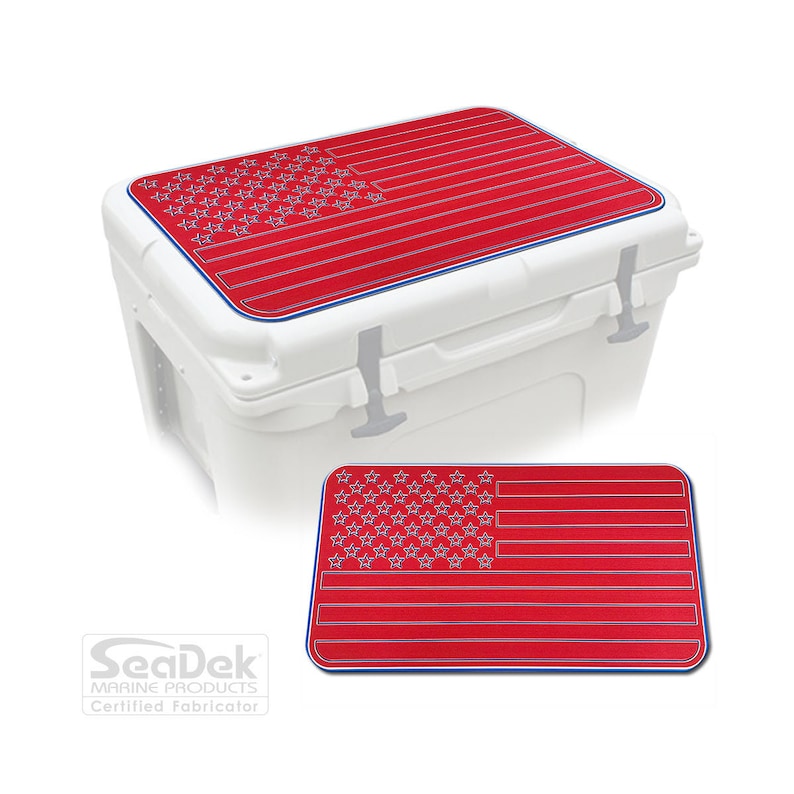 K&ouml;nnte beinhalten: Eine wei&szlig;e K&uuml;hlbox mit einem rot-blauen Design der amerikanischen Flagge auf dem Deckel. Das Flaggen-Design wird auch separat gezeigt. Die K&uuml;hlbox hat eine blaue Umrandung und silberne Verschl&uuml;sse. Das SeaDek Marine Products Logo ist enthalten.