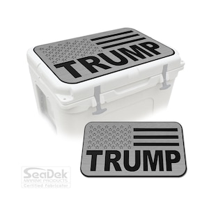 May include: A white cooler with a gray lid featuring a design of the American flag and the name "TRUMP" in bold black letters. A smaller version of the lid design is also shown.