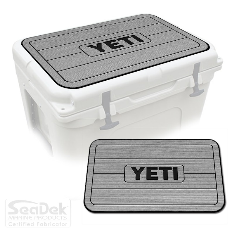 May include: Gray and black Yeti cooler lid and mat. The lid and mat have a wood-grain pattern and the Yeti logo is printed in black.