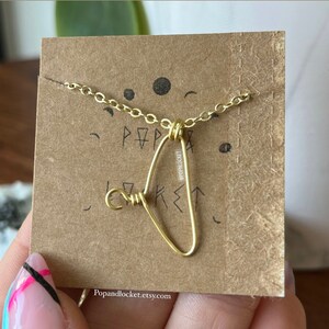 May include: A gold necklace with a heart-shaped pendant made of wire. The pendant is on a card with the text "Pop & Locket" and the social media handle "@popandlocket".