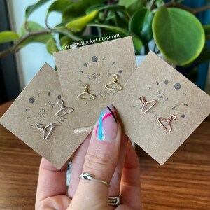 May include: Three small wire hangers in different colors: silver, gold, and copper. The hangers are displayed on small cards with the text "Pop & Lock" and a moon and star design.
