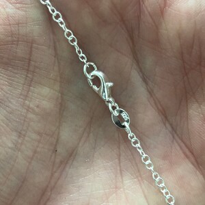 May include: A silver chain necklace with a lobster clasp and a small round tag with the number 925 stamped on it.