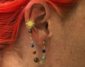May include: Gold ear cuff with a sun design and a chain with colorful beads and small metal spheres. The chain is attached to a small gold hoop earring.