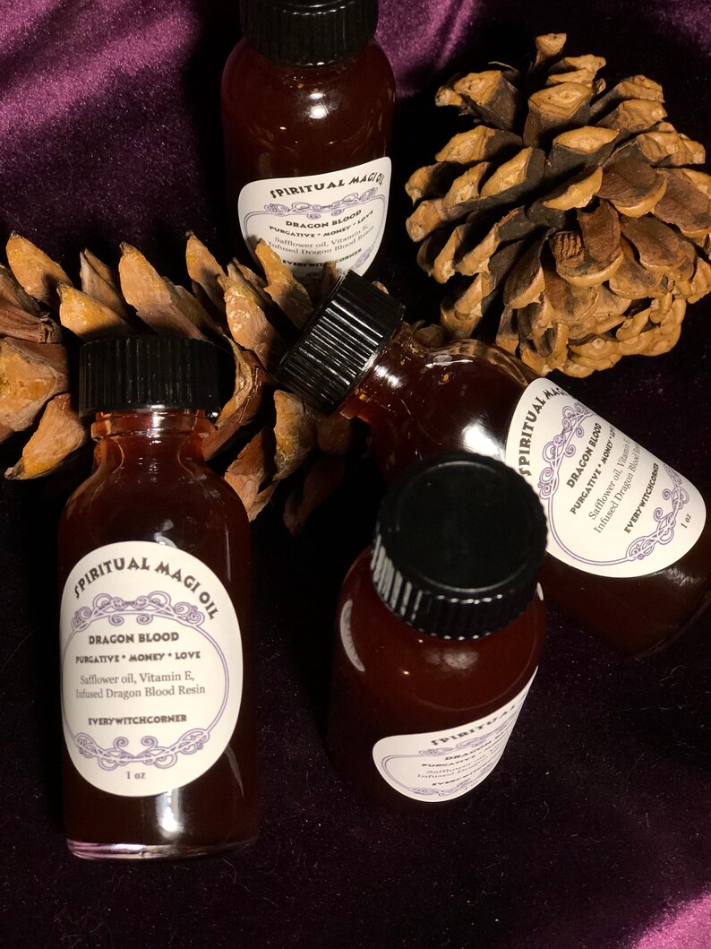 May include: Four small glass bottles with black lids filled with a dark red liquid. Each bottle has a white label with black text that reads "SPIRITUAL MAGI OIL" and "DRAGON BLOOD PURGATIVE MONEY LOVE Safflower oil, Vitamin E, Infused Dragon Blood Resin EVERYWITCHCORNER 1 oz".
