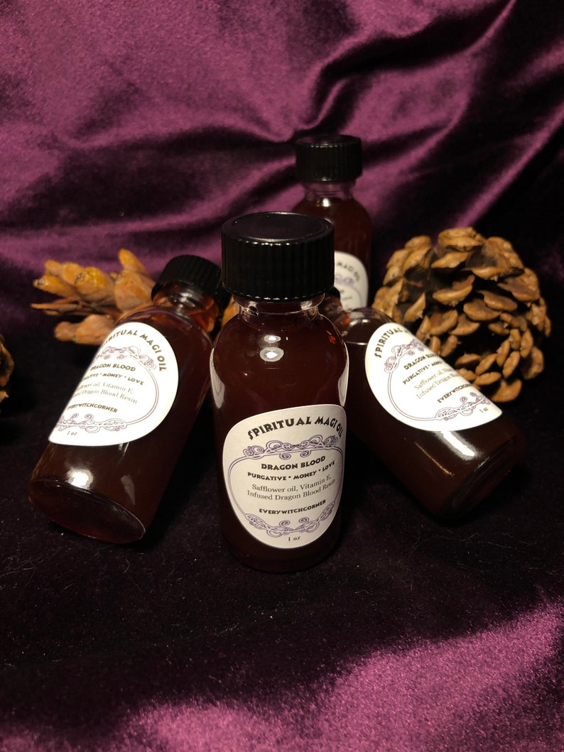May include: Three small glass bottles with black lids and labels. The labels are white with black text and a decorative border. The bottles contain a dark red liquid. The labels read "Spiritual Magic Oil", "Dragon Blood", "Purgative Money Love", "Safflower oil, Vitamin E, Infused Dragon Blood Resin", and "Every Witch Corner".