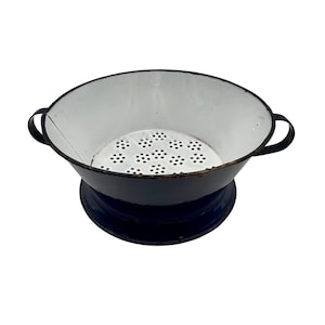 May include: A vintage blue and white enamel colander with a strainer base. The colander has two handles and a white interior.