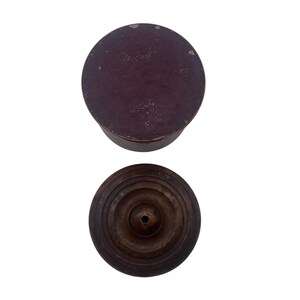 May include: A wooden box with a dark brown lid and a concentric circle design on the bottom. The lid is a deep burgundy color.