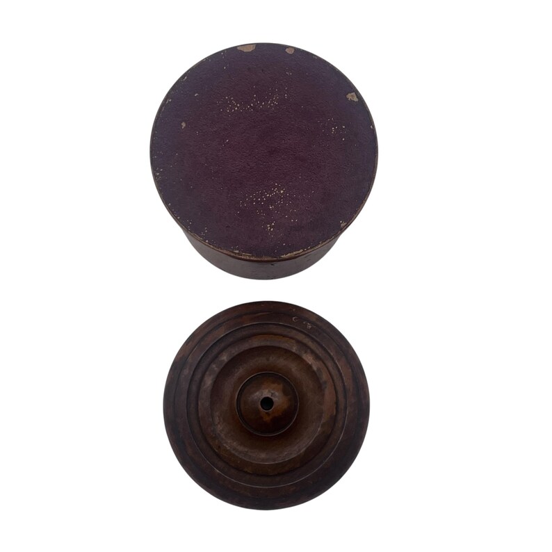 May include: A wooden box with a dark brown lid and a concentric circle design on the bottom. The lid is a deep burgundy color.
