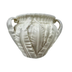 May include: White ceramic planter with two handles and a fern leaf design.