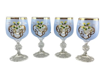 May include: Set of four blue glass wine glasses with gold trim and painted floral designs.