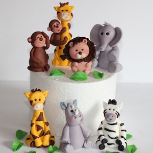 May include: A set of 8 fondant animal cake toppers, including a giraffe, lion, monkey, elephant, rhino, and zebra. The toppers are perfect for a jungle-themed birthday cake.
