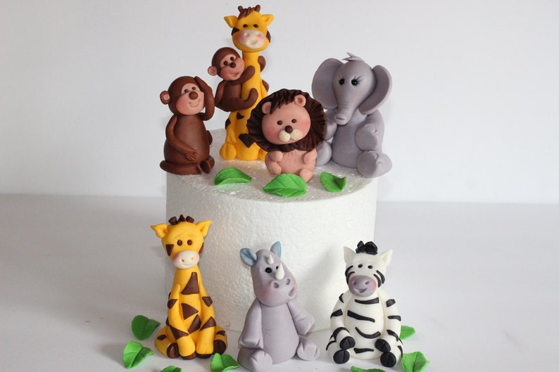 May include: A set of 8 fondant animal cake toppers, including a giraffe, lion, monkey, elephant, rhino, and zebra. The toppers are perfect for a jungle-themed birthday cake.