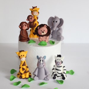 May include: A set of seven fondant animal cake toppers, including a giraffe, monkey, lion, elephant, rhino, zebra, and leaves. The toppers are perfect for a jungle-themed birthday cake.