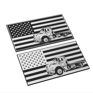 Op de afbeelding: Twee zwart-witte metalen borden met een Amerikaans vlagontwerp en een silhouet van een sleepwagen. De sleepwagen heeft de tekst "Lumpy's" aan de zijkant.