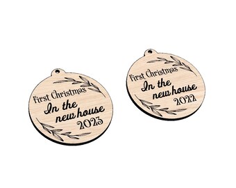 May include: Two round wooden ornaments with the text "First Christmas In the new house 2023" and a decorative leaf design.