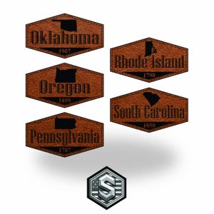 Puede incluir: Una colección de parches de cuero marrón con contornos de estados y texto. Los parches presentan los estados de Oklahoma, Oregón, Pensilvania, Rhode Island y Carolina del Sur, junto con sus años de fundación. Un logotipo plateado y azul está en la parte inferior.