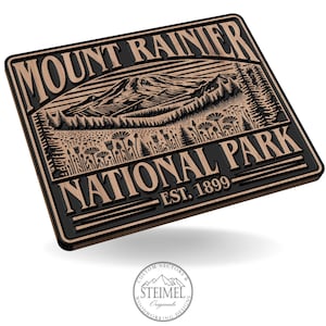 May include: A wooden sign with a black background and brown lettering. The sign reads "Mount Rainier National Park Est. 1899". The sign features a stylized image of Mount Rainier and surrounding forest.