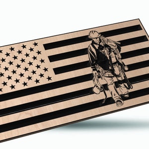 May include: A wooden cutout of an American flag with a silhouette of a construction worker carrying tools. The flag is black and brown with a white background. The worker is wearing a hard hat and carrying a tool belt, a hammer, and a level.