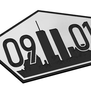 Puede incluir: Un letrero de metal en forma de estrella de cinco puntas de color plateado con una silueta negra del horizonte de la ciudad de Nueva York y la fecha "091101" en negro.