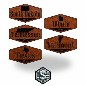 Peut inclure: Plusieurs écussons en cuir marron avec les contours et les noms des États : Dakota du Sud, Tennessee, Texas, Utah et Vermont. Chaque écusson comprend le nom de l'État et l'année d'accession à l'État. Un logo argenté et bleu est en bas.