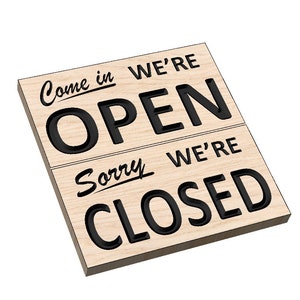 Könnte beinhalten: Ein Holzschild mit schwarzem Text, der auf der oberen Hälfte "Come in we're open" und auf der unteren Hälfte "Sorry we're closed" lautet.