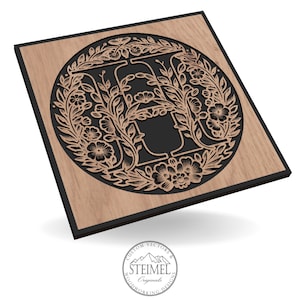 May include: Wooden wall art featuring a floral design around a letter "A" in a circular pattern. The letter and floral elements are black, set against a light brown wood grain background. The piece has a black border and the Steimel Originals logo.