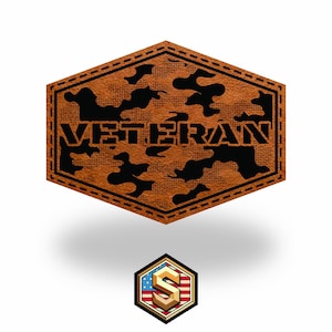 May include: A brown leather patch with the word "VETERAN" in black block letters. The patch has a camouflage pattern and a stitched border. A smaller badge with an American flag design is below.