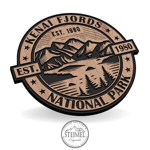 Peut inclure: Une enseigne en bois avec un motif noir et blanc d'une chaîne de montagnes et d'un lac. L'enseigne porte les inscriptions "Kenai Fjords National Park" et "Est. 1980".