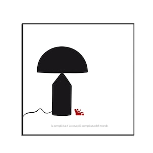 May include: A black and white illustration of a lamp with a large, round shade. The lamp is sitting on a white surface with a small red armchair in the background. The text "la semplicità è la cosa più complicata del mondo" is written below the lamp.