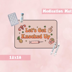 Puede incluir: Una alfombra de medicamentos marrón claro de 30,5 x 45,7 cm con el texto "Let's Get Knocked Up" en una fuente retro. La alfombra presenta una variedad de ilustraciones, incluyendo una jeringa, una piña, un útero, una papa frita y un corazón.