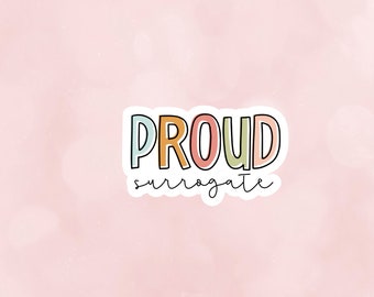 May include: A sticker with the word "PROUD" in rainbow colors and the word "surrogate" written in black below it.