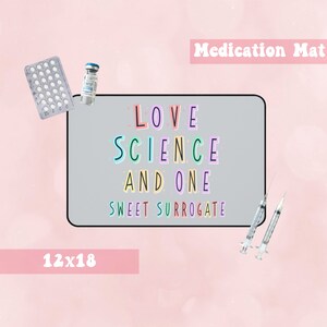 Puede incluir: Una alfombrilla gris para medicamentos de 30,5 x 45,7 cm con el texto "LOVE SCIENCE AND ONE SWEET SURROGATE" en letras de colores. La alfombrilla está rodeada de suministros médicos, como un blíster de pastillas, un vial y dos jeringas.