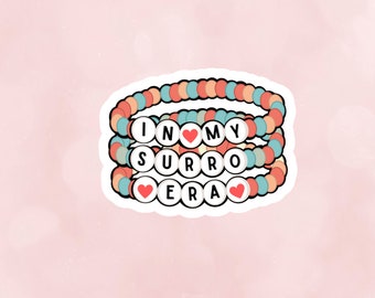 May include: Three colorful beaded bracelets with the words "IN MY SURRO ERA" and red heart charms.