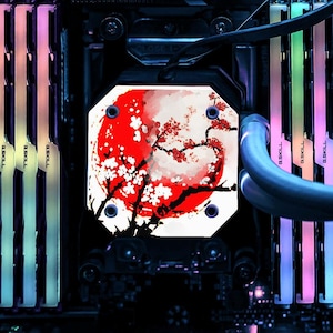 May include: A computer component featuring a red and white floral design with a red sun. The component is surrounded by colorful LED-lit RAM sticks. The design is reminiscent of Japanese art.