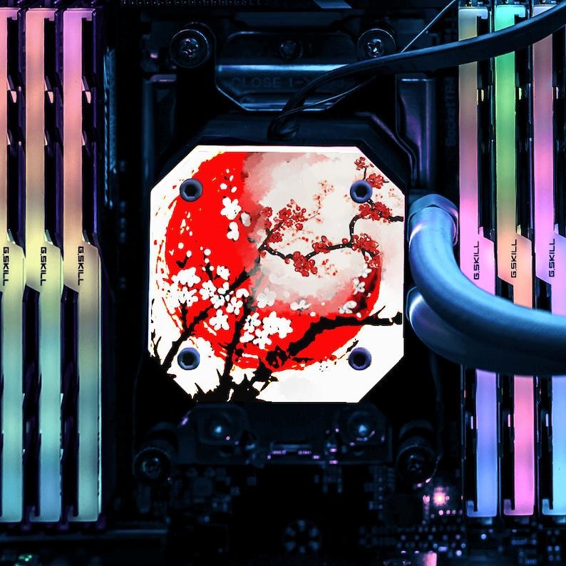 May include: A computer component featuring a red and white floral design with a red sun. The component is surrounded by colorful LED-lit RAM sticks. The design is reminiscent of Japanese art.