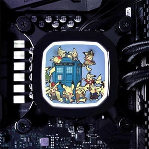 May include: A computer cooling fan with a white light, featuring a cartoon image of a blue police box with multiple yellow Pikachu characters surrounding it. The text "POLICE BOX" is visible on the police box.