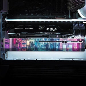 Może przedstawiać: Czarno-srebrna karta graficzna z nadrukowaną sceną neonowego miasta. Karta ma logo MSI i biały pasek świateł LED.